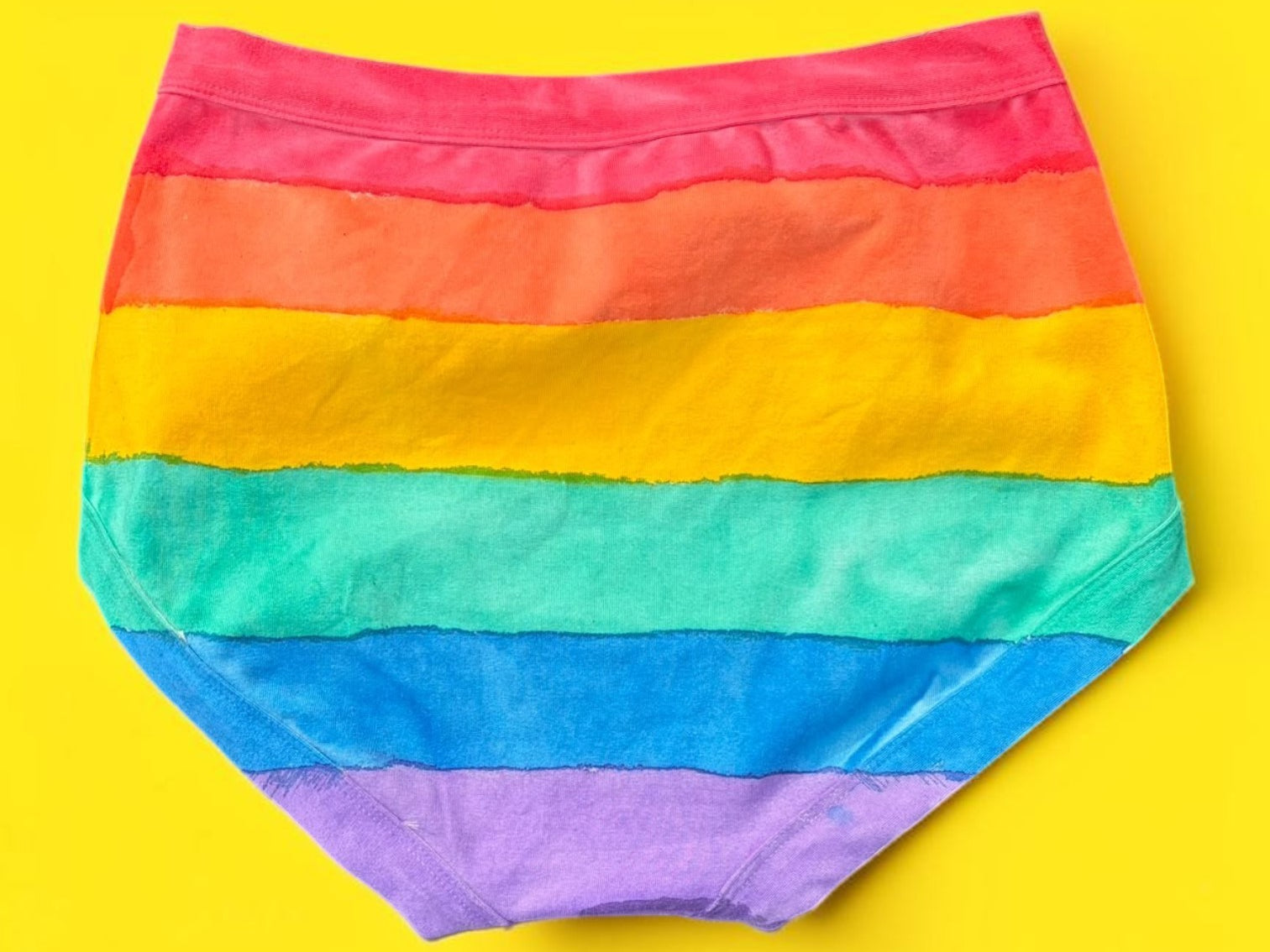 The back of the Rainbow striped originals laid flat on a bright yellow background.