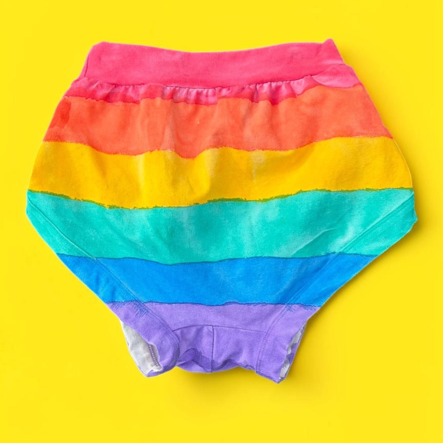 Rainbow-striped Thunderpant briefs back laid flat on a bright yellow background.