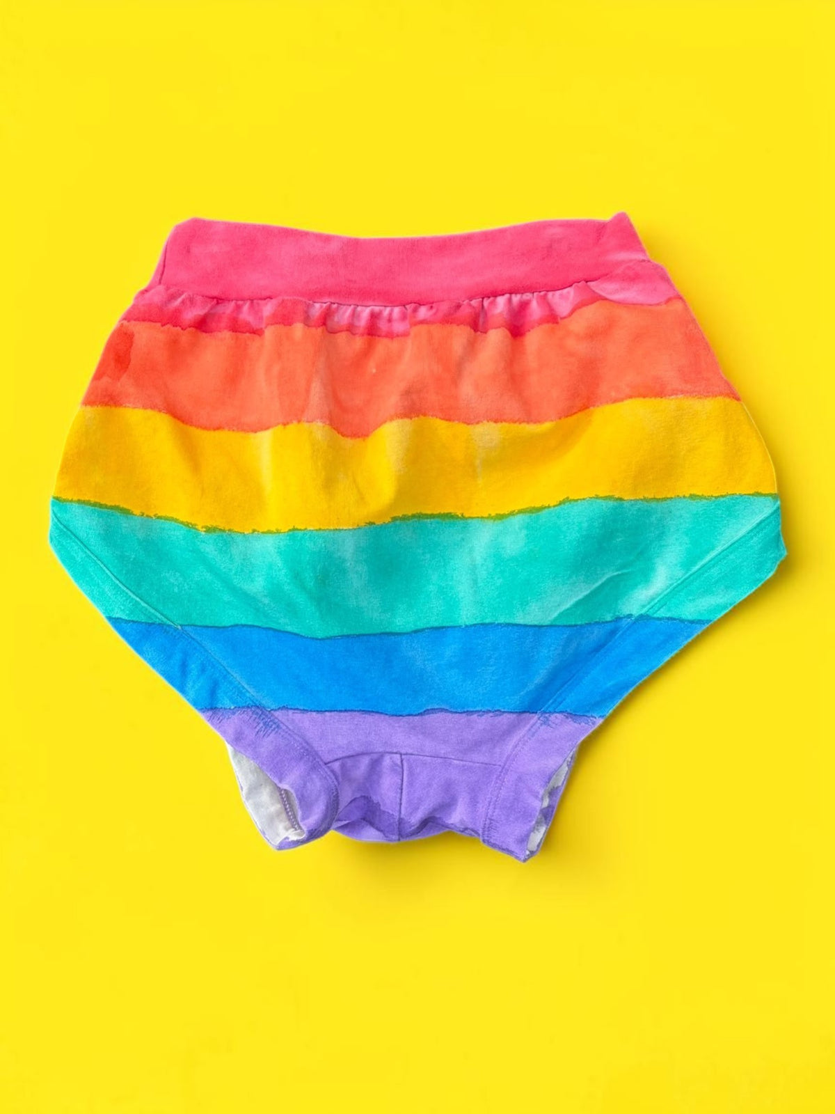 Rainbow-striped Thunderpant briefs back laid flat on a bright yellow background.